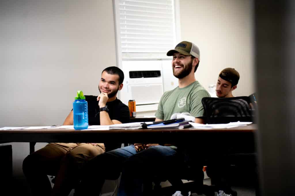 two students smiling as they're listening.