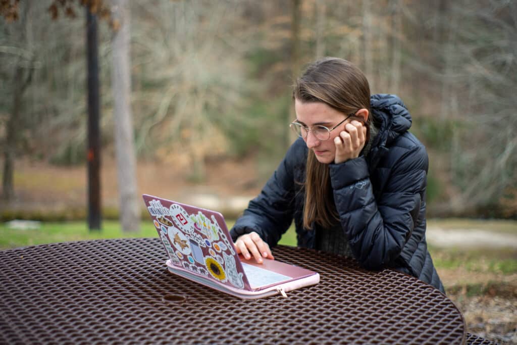 Toccoa Falls College student using laptop outside