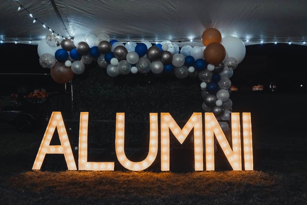 A decorated, illuminated Alumni sign