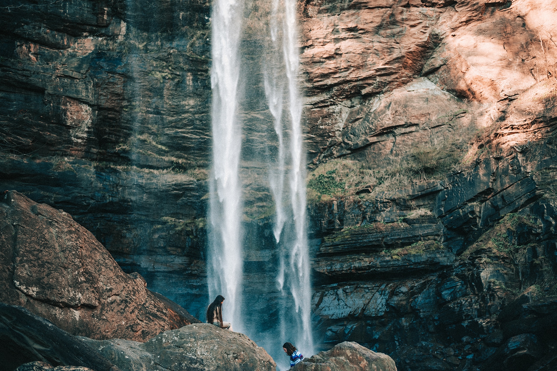 Students climb on rocks underneath Toccoa Falls