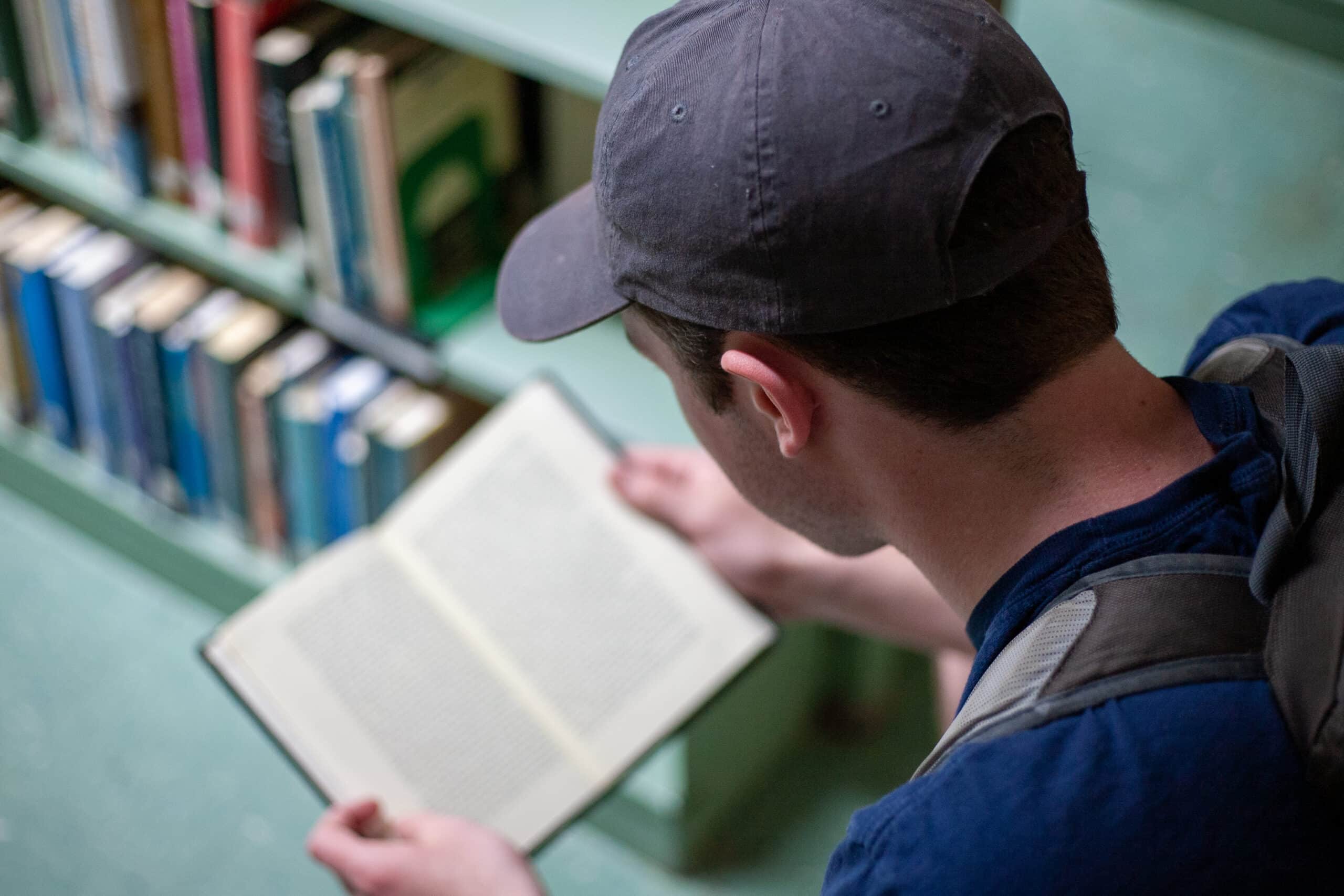 Man in a blue ball cap reading a book