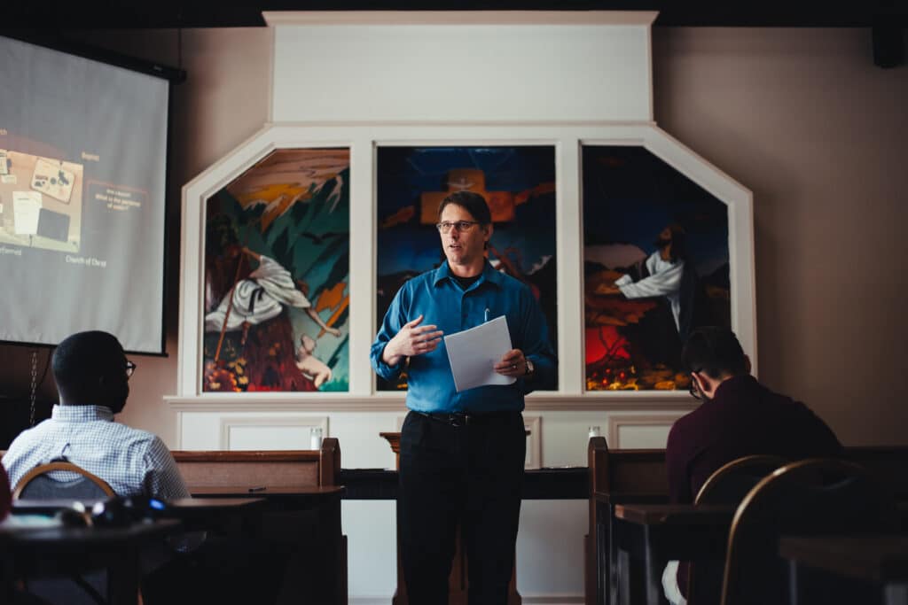 A minister gives a lecture to a classroom inside a chapel