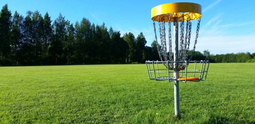A disc golf net sits in a field