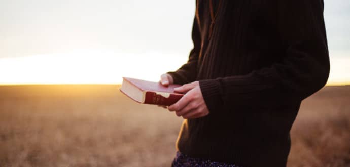 Man walking in field with bible