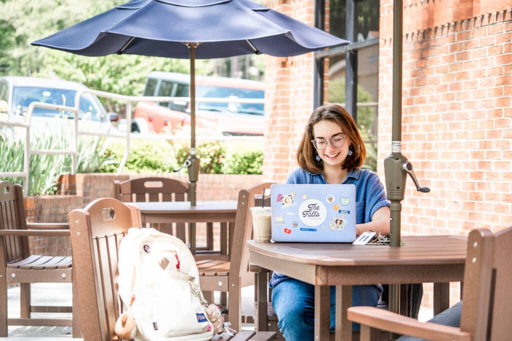 student smiling working on laptop