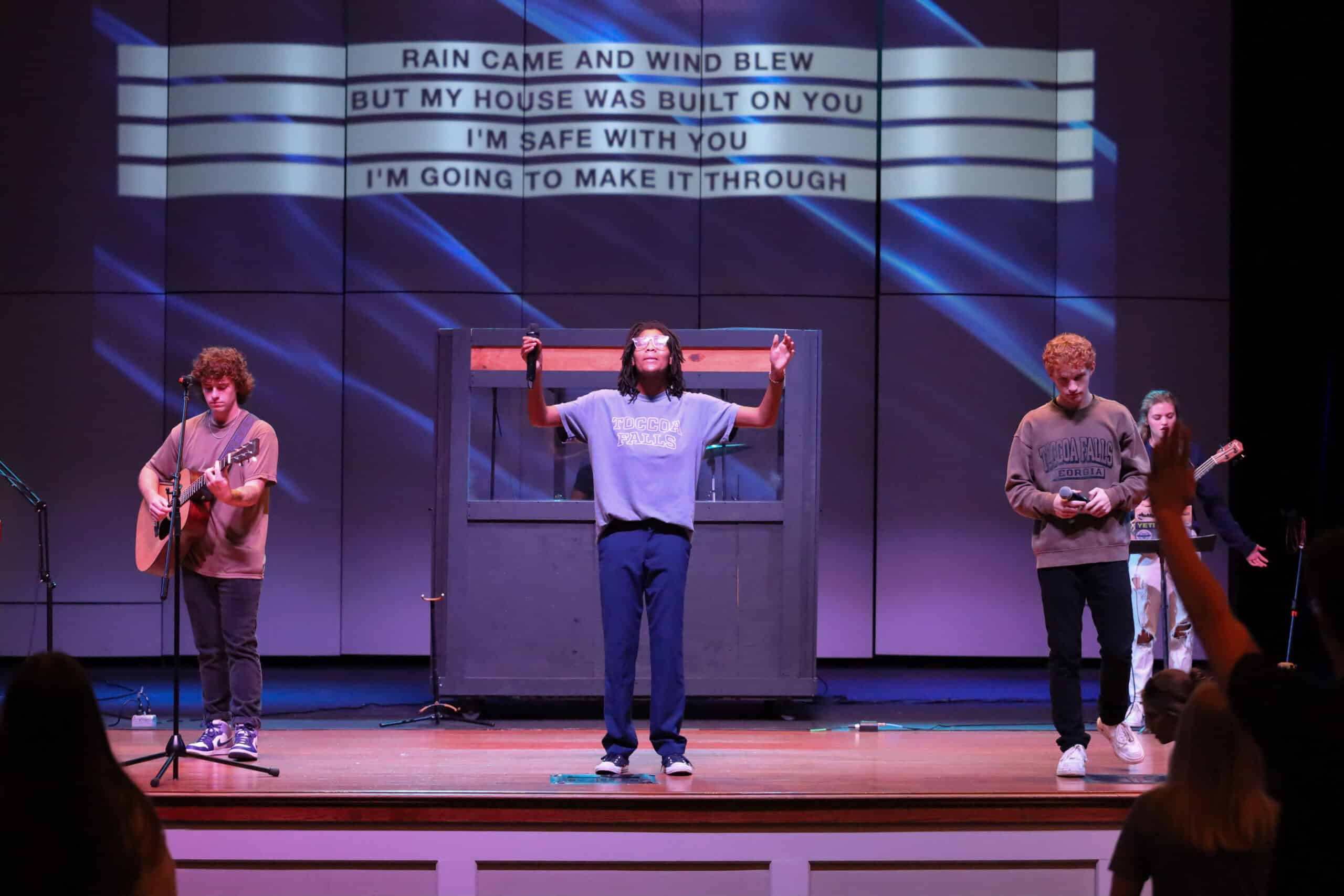 Three people worshipping on stage