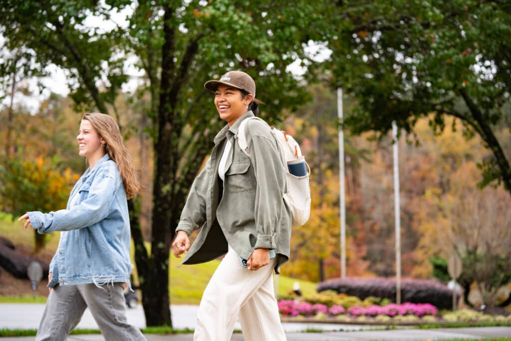 two students smiling brightly as they're headed to Chapel.