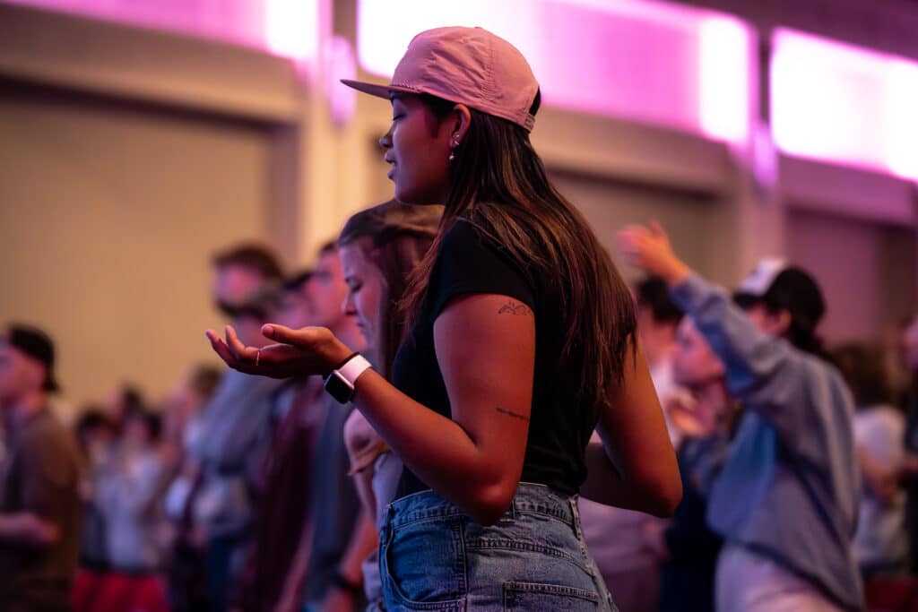Students lifting their hands in praise during worship.