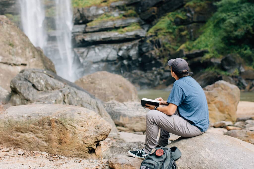 A student reading the Bible under the falls.